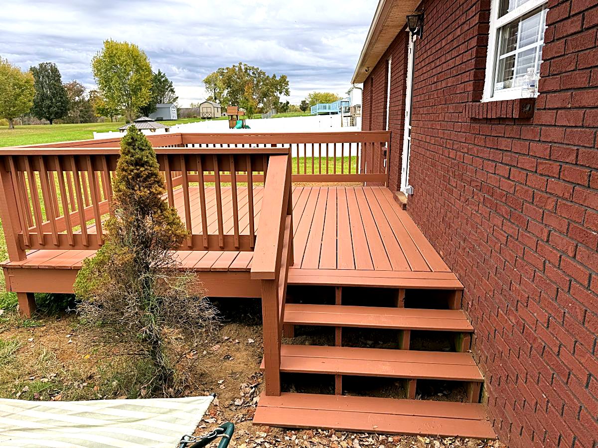 Painted deck with new steps beside a brick home